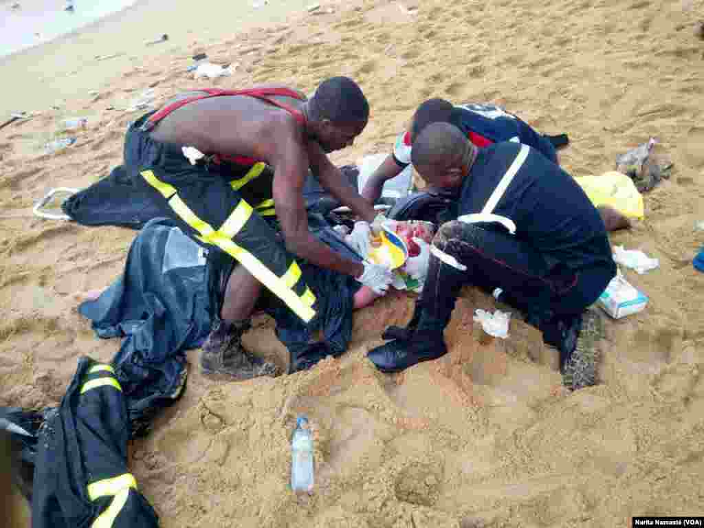 Des pompiers assistant un survivant du crash d’avion au bord de la mer au Port Bouet, au large d’Abidjan, Côte d’ivoire, 14 octobre 2017. (VOA/Narita Namasté)