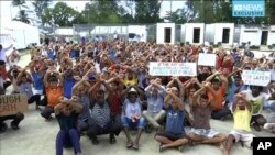 FILE - This photo made from Australia Broadcasting Corporation video taken Oct. 31, 2017, shows asylum seekers protesting the possible closure of their detention center on Manus Island, Paua New Guinea. 