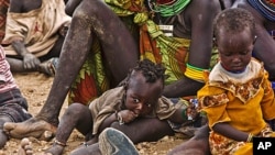 In Kenya, Turkana women and their children wait to receive relief food supplies near the Kakuma Refugee Camp, northwest of Kenya's capital Nairobi, August 8, 2011