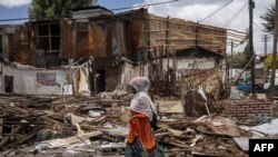 አንዲት ሴት፣ ከፍተኛ ፈረሳ በተካሄደበት የአዲስ አበባ ታሪካዊው ፒያሳ ሰፈር መሃል ስታልፍ - መጋቢት 14፣ 2024