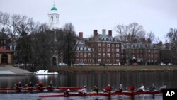 FILE - Rowers pass the campus of Harvard University as they move down the Charles River in Cambridge, Mass., March 7, 2017. Harvard and the group Students for Fair Admissions will go to trial in a lawsuit alleging discrimination against Asian-American ap