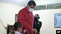 Acompañado de sus nietas, el presidente de Venezuela, Nicolás Maduro, emite su voto durante las elecciones primarias del partido gobernante, el Partido Socialista Unido de Venezuela, en Caracas, el 8 de agosto de 2021.