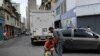 Men siphon gasoline from a car in the San Juan neighborhood of Caracas, Venezuela, Jan. 19, 2021.