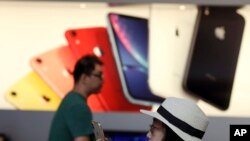 A customer looks at her iPhone in a store of U.S. tech company Apple in Beijing, May 10, 2019. 