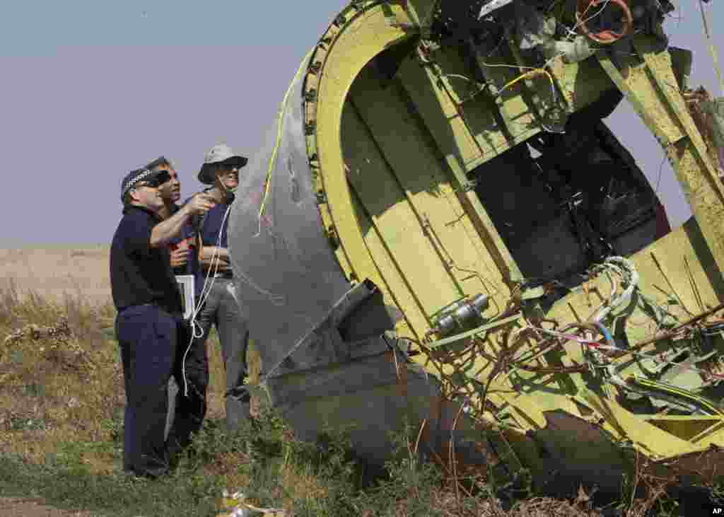 Australian and Dutch experts examine a piece of the Malaysia Airlines plane, near the village of Hrabove, Donetsk region, eastern Ukraine, Aug.1, 2014. 