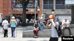 Una mujer mayor se sienta en una esquina usando tapabocas durante la cuarentena por el coronavirus en Caracas, Venezuela. Abril 27, 2020