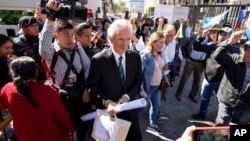 Los partidarios del periodista encarcelado José Rubén Zamora y la prensa rodean a Zamora cuando sale esposado del tribunal en la Ciudad de Guatemala, el miércoles 21 de febrero de 2024.
