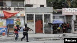 La gente se aglomera en una esquina mientras la policía patrulla las calles después de que pandilleros intentaran atacar una comisaría, en Puerto Príncipe, Haití, el 25 de abril de 2023.