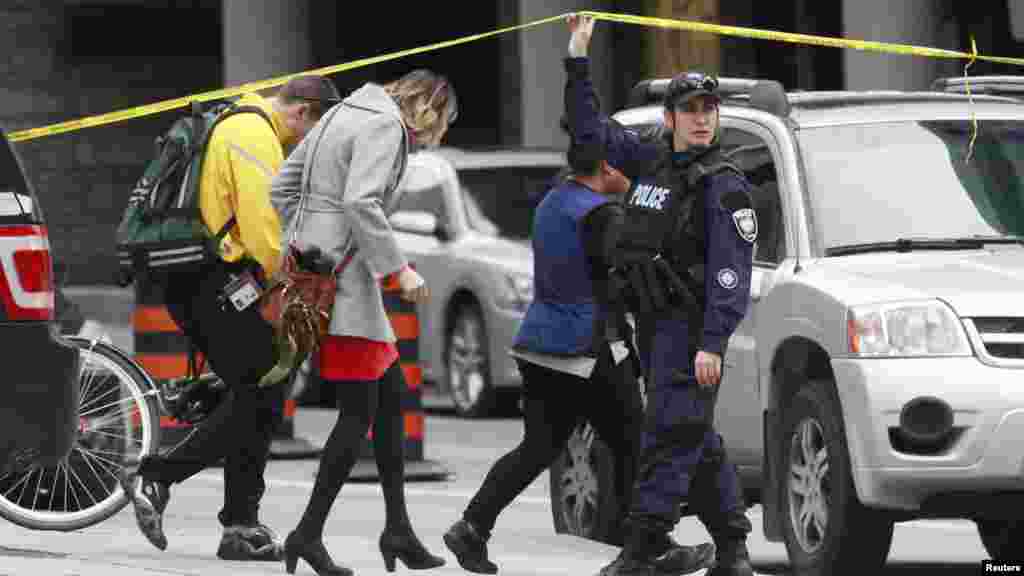 Un agent de la police d'Ottawa soulève le ruban de sécurité pour laisser les piétons quitter le centre-ville après une fusillade à Ottawa, le 22 Octobre 2014. REUTERS/Blair Gable