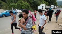 Hondureños que participan en una nueva caravana de migrantes que se dirigirá a los Estados Unidos, caminan cerca del paso fronterizo de Corinto con Guatemala, en Corinto, Honduras, 30 de marzo de 2021.
