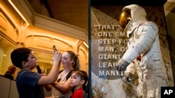 Para pengunjung memotret pakaian antariksa astronot Neil Armstrong yang dipakainya saat Apollo 11 mendarat di Bulan, dipajang di Museum Smithsonian di Washington DC 