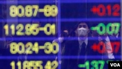 Seorang pria mengamati angka-angka indeks Nikkei pada sebuah layar di Tokyo, Kamis (17/3). Indeks Nikkei naik 5,7 persen yang memulihkan hampir sepertiga penurunan sebelumnya pekan ini.
