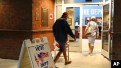 FILE - Voters walk into a polling station for the Florida presidential primary in Bonita Springs, Fla.
