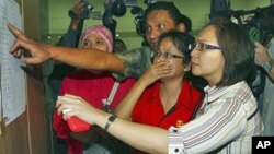 Relatives inspect the list of passengers on board a missing Russian airplane at Halim Perdanakusuma Airport in Jakarta, Indonesia, May 9, 2012.