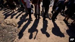 ARCHIVO - Migrantes esperan ser procesados por la patrulla fronteriza de EEUU, en Eagle Pass, Texas. El arresto de un migrante venezolano por el asesinato de una estudiante de enfermería en Georgia conmocionó al país.