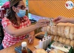 Una compradora paga con un billete de 10 dólares en un mercado abierto en el oeste de Caracas. Foto: Luisana Solano - VOA.