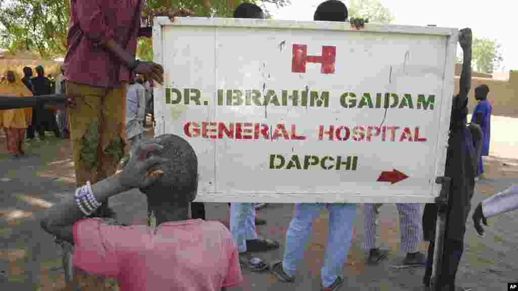 Les gens se rassemblent à l'extérieur de l'hôpital général où les filles kidnappées libérées sont soignées, à Dapchi, au Nigeria, le 21 mars 2018.