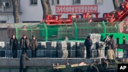 北韓公民在北韓新義州河岸的船上卸貨。新義州對面就是中國與北韓的邊境城市丹東。 (資料照。攝於2011年12月30日。)