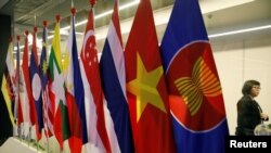 Seorang perempuan berjalan melintas di depan bendera negara-negara anggota ASEAN dalam KTT ASEAN di Suntec Convention Centre di Singapura, 11 November 2018. 