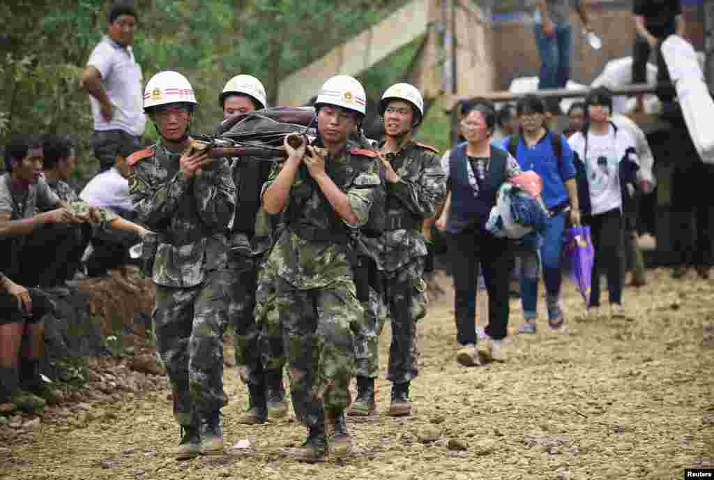 Paramilitary policemen carry an injured resident with a makeshift stretcher after an earthquake hit Longtoushan township of Ludian county, Yunnan province, Aug. 4, 2014. 