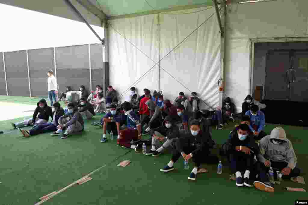 Los niños inmigrantes que dieron positivo por la enfermedad del COVID-19 se sientan en el suelo en el centro de detención en Donna, Texas, la principal instalación para niños no acompañados en el Valle de Río Grande.