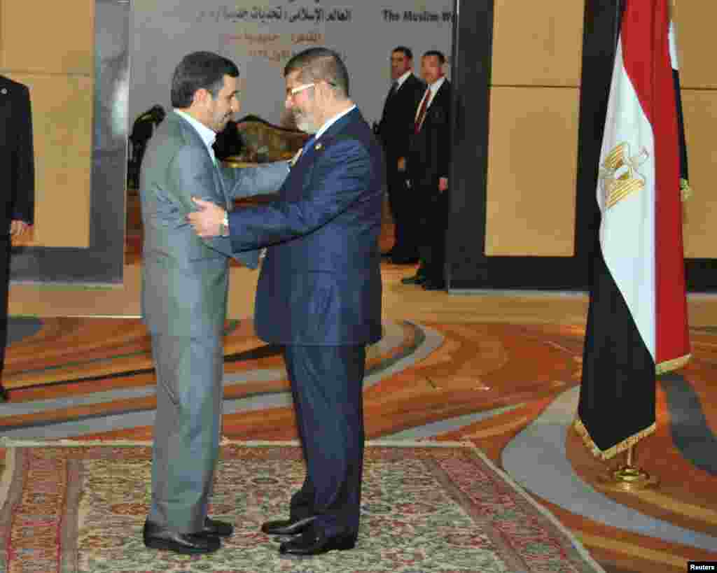Egyptian President Mohamed Morsi greets Iran's President Mahmoud Ahmadinejad before the opening OIC summit in Cairo, February 6, 2013.