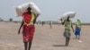 Women walk back to their homes after receiving food distributed by ICRC at a site in Leer County region of South Sudan, Tuesday, April 11, 2017. 