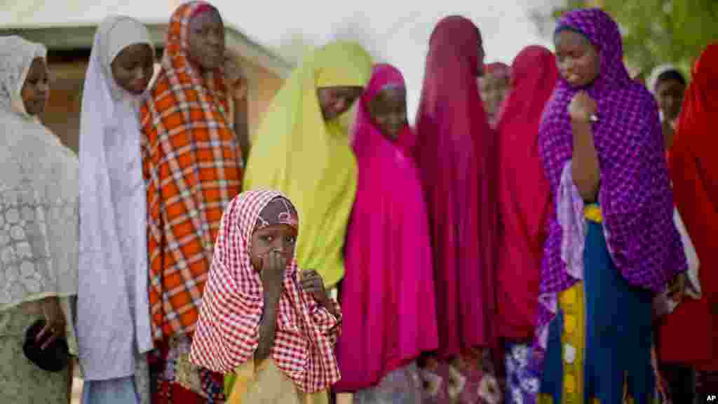Une petite fille nigériane de la tribu Hausa se tient près de la file où sa mère est alignée avec d’autres électeurs, attendant la validation de leur carte de vote, à un bureau de vote situé dans une école islamique de Daura, ville natale du candidat de l'opposition le général Muhammadu Buhari, samedi 28 mars 2015.