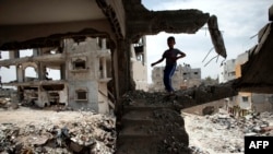 FILE - Palestinian boy plays amid the rubble of his familiy's former house, which was destroyed during the 50-day war between Israel and Hamas militants in the summer of 2014, eastern Gaza City, May 11, 2015.