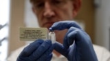 FILE - A researcher holds a vial of an experimental Ebola vaccine in Oxford, England Wednesday Sept. 17, 2014.