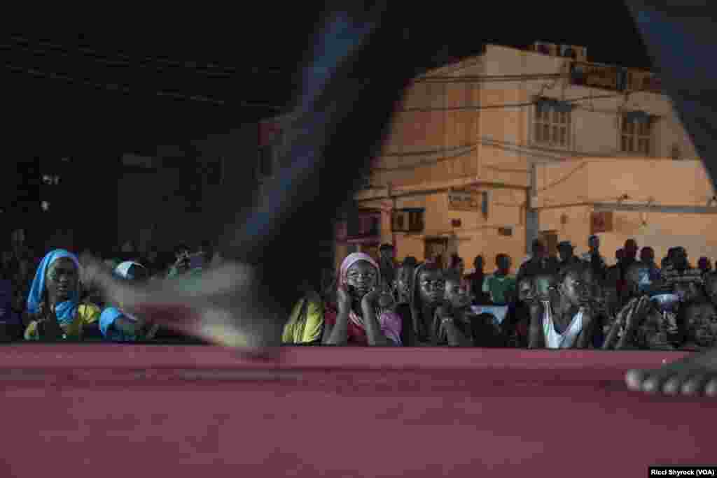 Local youth watch models on the catwalk at Dakar Fashion Week's "Street Show," which is open to the public, in the Niary Tally neighborhood, June 29, 2017.