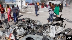 Des Somaliens passent devant des débris après un attentat suicide à la voiture piégée contre un bâtiment du gouvernement dans la capitale Mogadiscio, en Somalie, samedi 23 mars 2019. Des hommes armés d'Al-Shabab ont pris d'assaut le bâtiment du gouvernement après l'attentat à la 