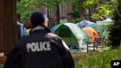 Un agente de la policía de la Universidad George Washington supervisa la zona en la que los estudiantes mantienen una protesta pro-Palestina por la guerra entre Israel y Hamás, el 26 de abril de 2024, en Washington. 