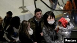 Security personnel wear face masks as they stand at the gate of the Shanghai Disney Resort, which announced that it will be closed indefinitely from Saturday, in Shanghai, Jan. 25, 2020.
