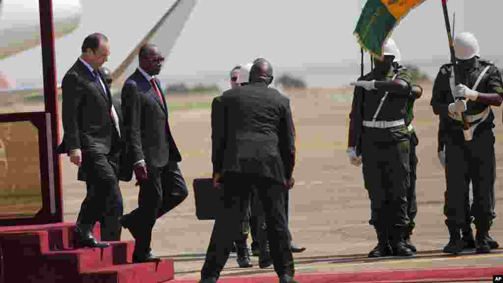 Le président français François Hollande, à gauche, et son homologue guinéen Alpha Condé passent en revue la garde d'honneur, à Conakry, en Guinée, vendredi 28 novembre 2014.