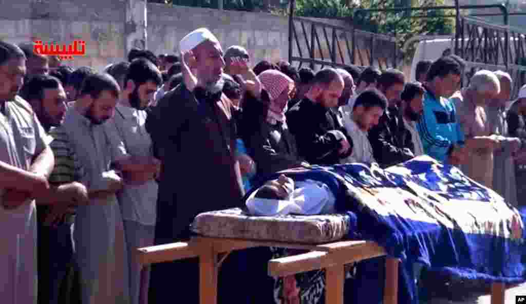 Syrians participate in the funeral prayer for Youssef Ghazi al-Sarmani, who was killed in fighting between rebel and government forces, May 27. The logo in red reads "Talbiseh".