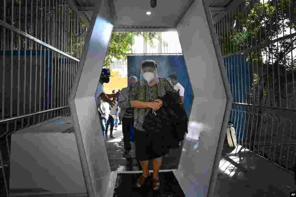 Una mujer con máscara protectora para protegerse de la propagación del nuevo coronavirus llega a votar en un colegio electoral para ecuatorianos que viven en Caracas, Venezuela, el domingo 7 de febrero de 2021.