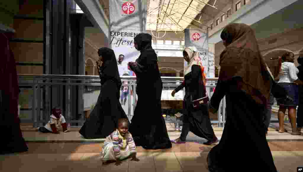Une jeune fille kenyane et son frère jouent sur le sol tandis que d'autres acheteurs sillonent à pied à travers le Westgate Shopping Mall, le 18 juillet 2015