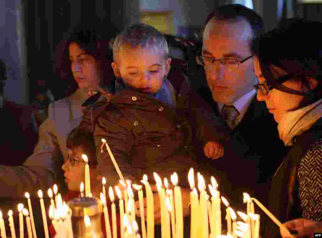 Seorang anak laki-laki Albania menyalakan lilin Natal di dalam gereja Katedral Orthodox Kebangkitan Yesus Kristus di Tirana (25/12).