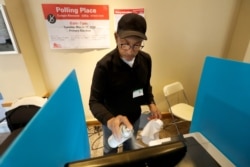 John Davis, a polling judge volunteer, sanitizes an electronic voting machine screen amid concerns about the COVID-19 coronavirus at a polling place in the Bronzeville neighborhood of Chicago, March 17, 2020.