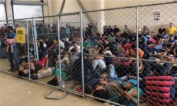 FILE - An overcrowded fenced area holding families at a Border Patrol station is seen in a still image from video in McAllen, Texas, June 10, 2019.