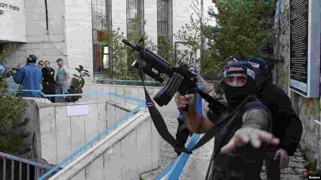 An Israeli police officer gestures as he holds a weapon near the scene of an attack at a Jerusalem synagogue, Nov. 18, 2014.