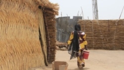 Une femme porte un seau d'eau au camp informel de Yawuri, à la périphérie de Maiduguri, capitale de l'État de Borno, le 29 mars 2021. (Audu Marte/AFP)
